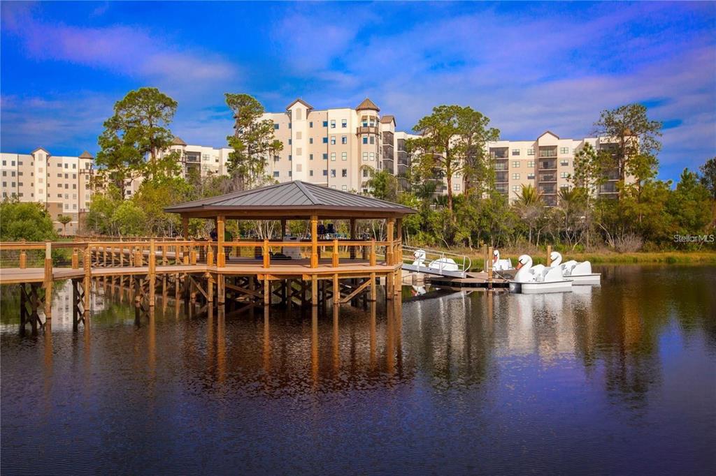 A wooden gazebo sits on a dock over a lake with swan-shaped pedal boats nearby — 14501 GROVE RESORT AVENUE UNIT 1440, WINTER GARDEN, FL
