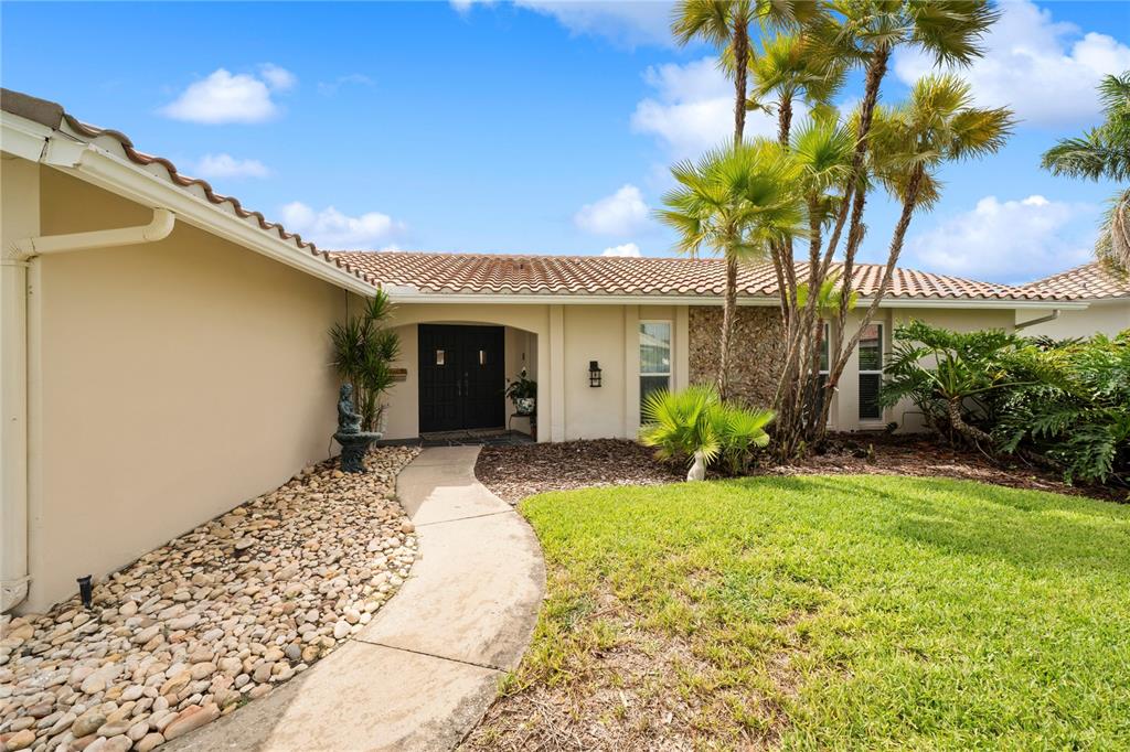 A beige house with a tile roof, palm trees, and a stone-lined walkway — 1924 MICHIGAN AVENUE NE, ST PETERSBURG, FL