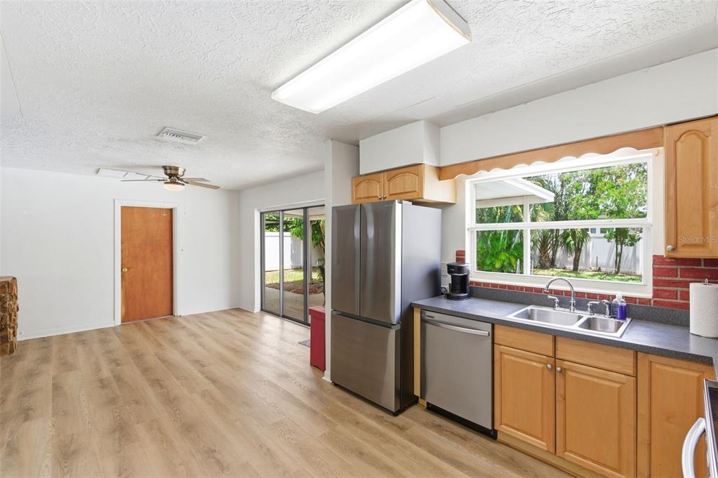 A kitchen with light wood cabinets, stainless steel appliances, and a view of the backyard — 10651 125TH AVENUE, LARGO, FL
