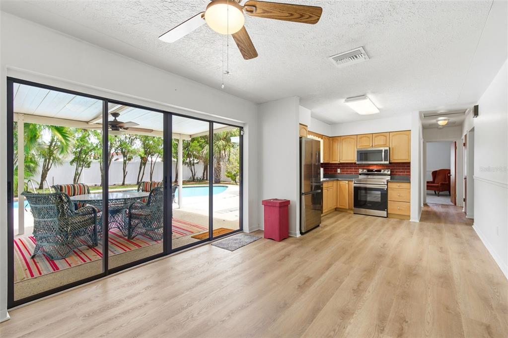 A kitchen with light wood cabinets and stainless steel appliances opens to a pool patio — 10651 125TH AVENUE, LARGO, FL