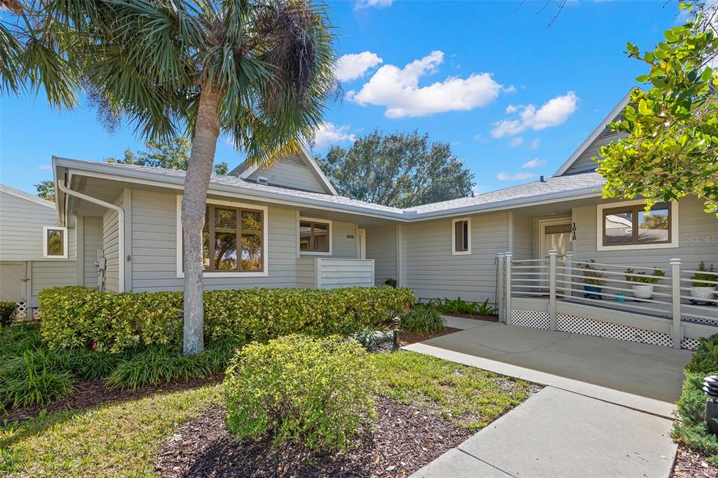 The exterior of a light-gray house features a wheelchair ramp leading to the front entrance — 1013 CARAVEL COURT, TARPON SPRINGS, FL