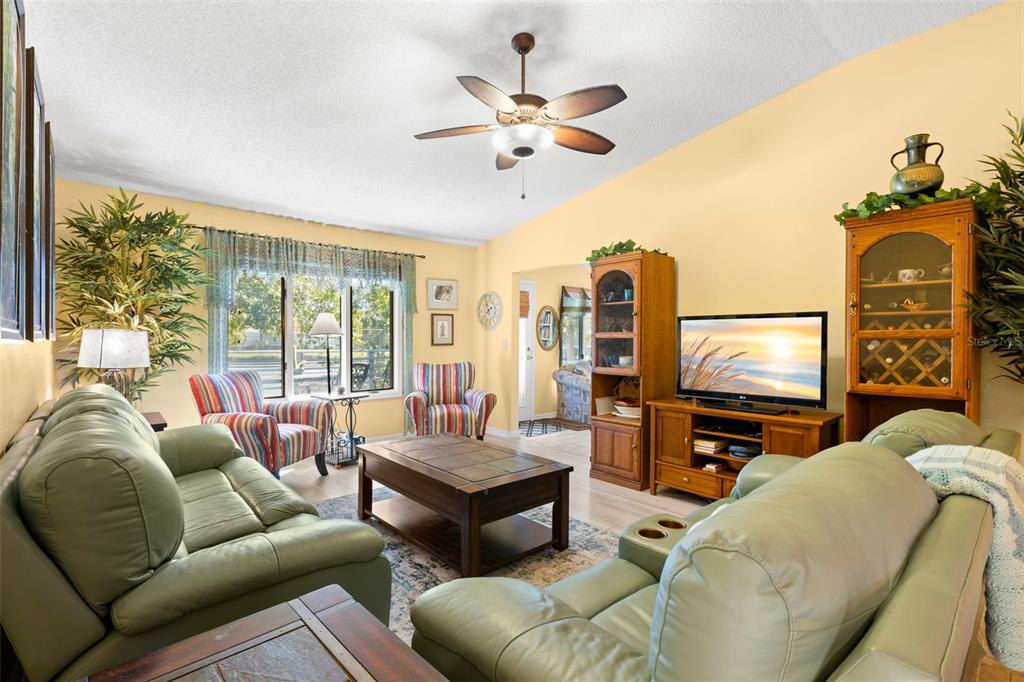 A living room with light green leather sofas, a wooden coffee table, and a ceiling fan — 1013 CARAVEL COURT, TARPON SPRINGS, FL