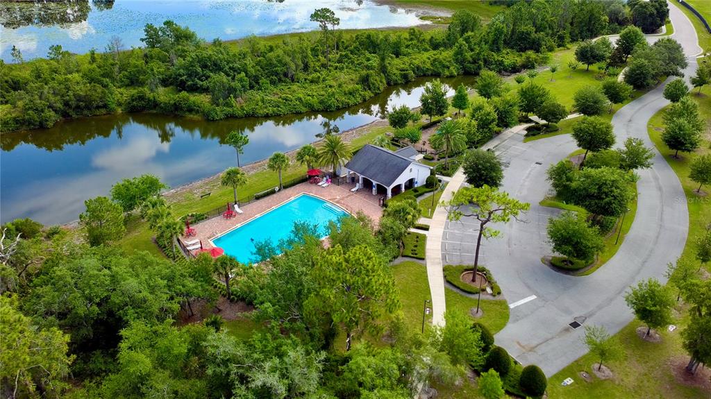 An aerial view shows a swimming pool and clubhouse surrounded by trees and a pond — 16337 SAINT AUGUSTINE STREET, CLERMONT, FL