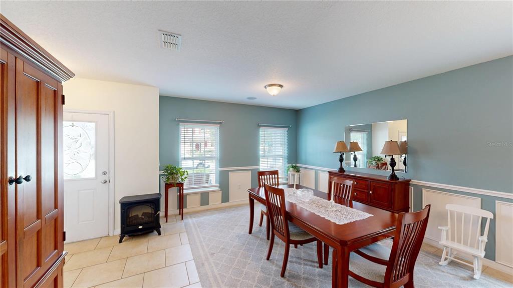 A dining room features a wooden table, blue walls, wainscoting, and a small fireplace — 16337 SAINT AUGUSTINE STREET, CLERMONT, FL