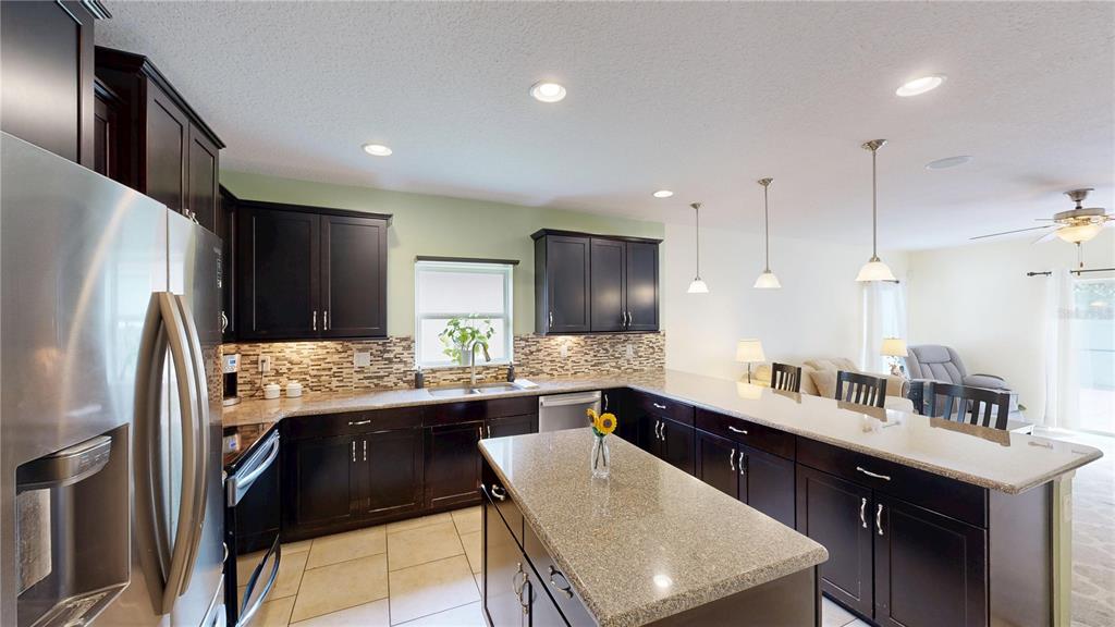 A kitchen features dark wood cabinets, granite countertops, a center island, and stainless steel appliances — 16337 SAINT AUGUSTINE STREET, CLERMONT, FL
