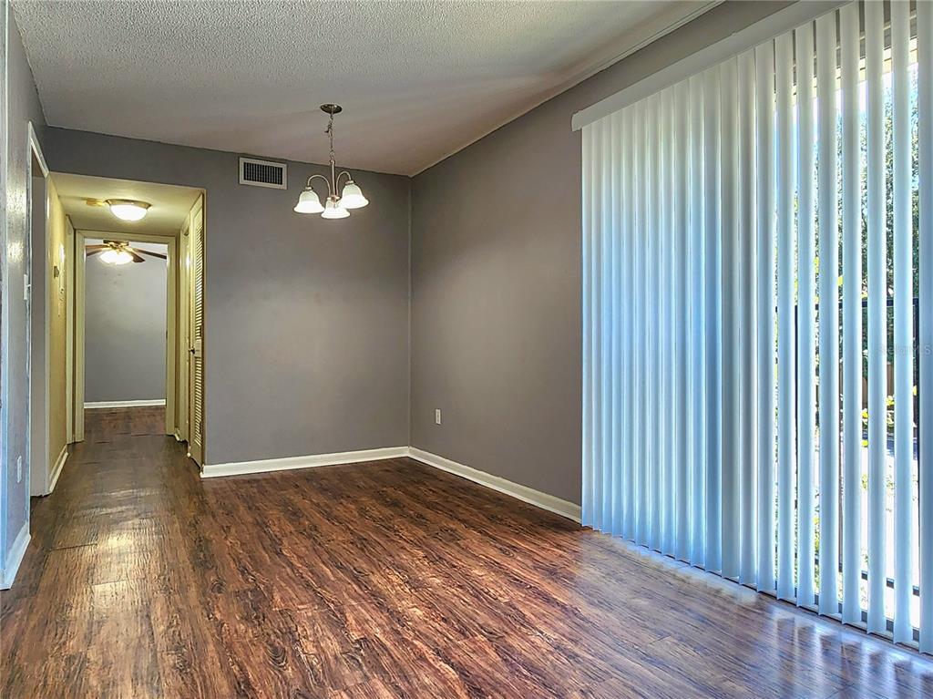 A dining room with wood-look flooring, gray walls, a chandelier, and vertical window blinds — 507 NW 39TH RD UNIT 237, GAINESVILLE, FL