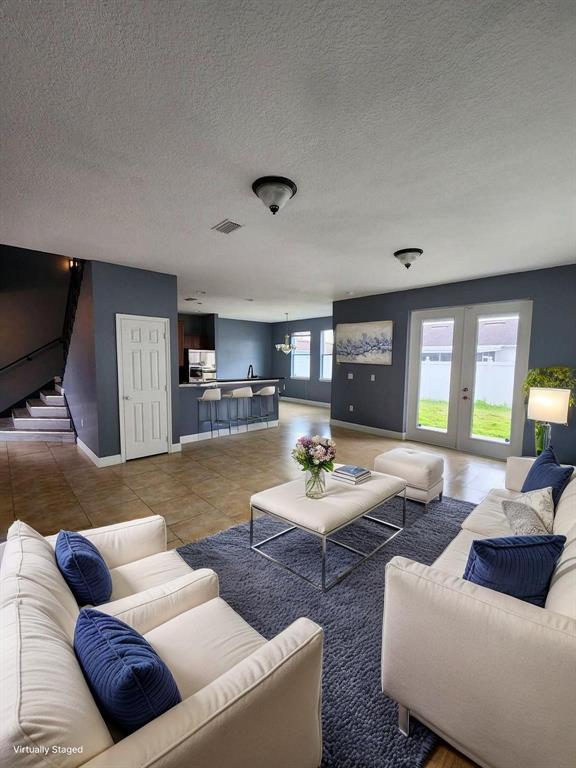 A living room with tile floors, blue walls, and white sofas faces a kitchen area — 328 DUNDEE DRIVE, KISSIMMEE, FL