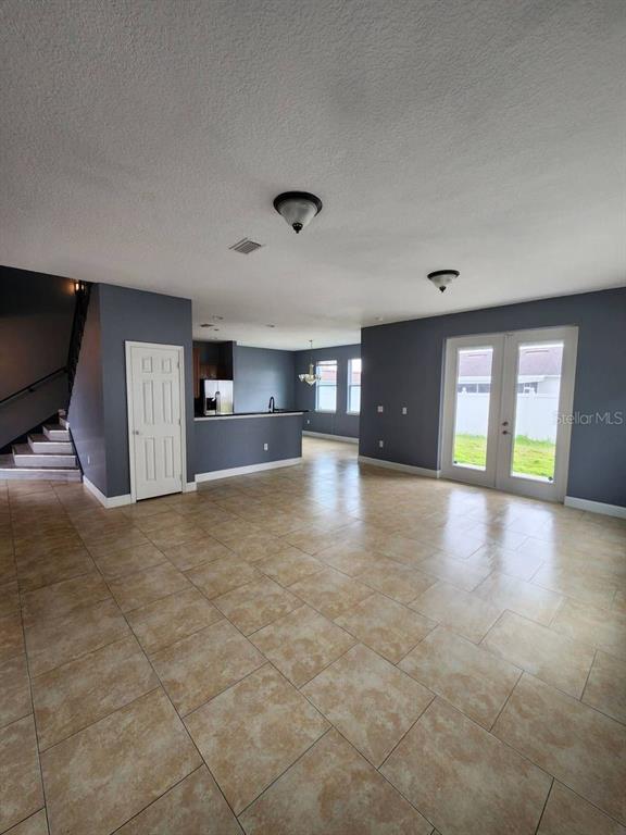 An open-concept living area features tile flooring, dark gray walls, a staircase, and glass doors — 328 DUNDEE DRIVE, KISSIMMEE, FL