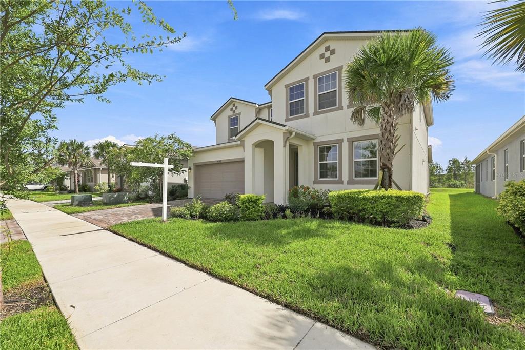 A two-story suburban house with a beige stucco exterior, a garage, and a front lawn — 19780 BLUE POND DRIVE, LUTZ, FL
