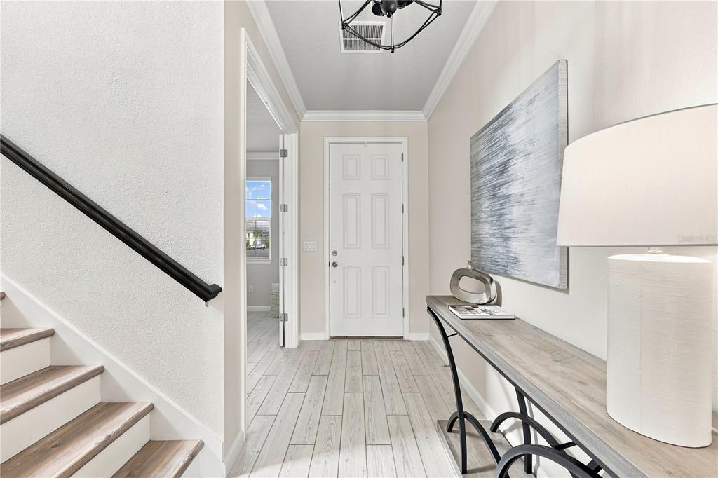 A bright entryway features a staircase, a console table, and a white front door — 19780 BLUE POND DRIVE, LUTZ, FL