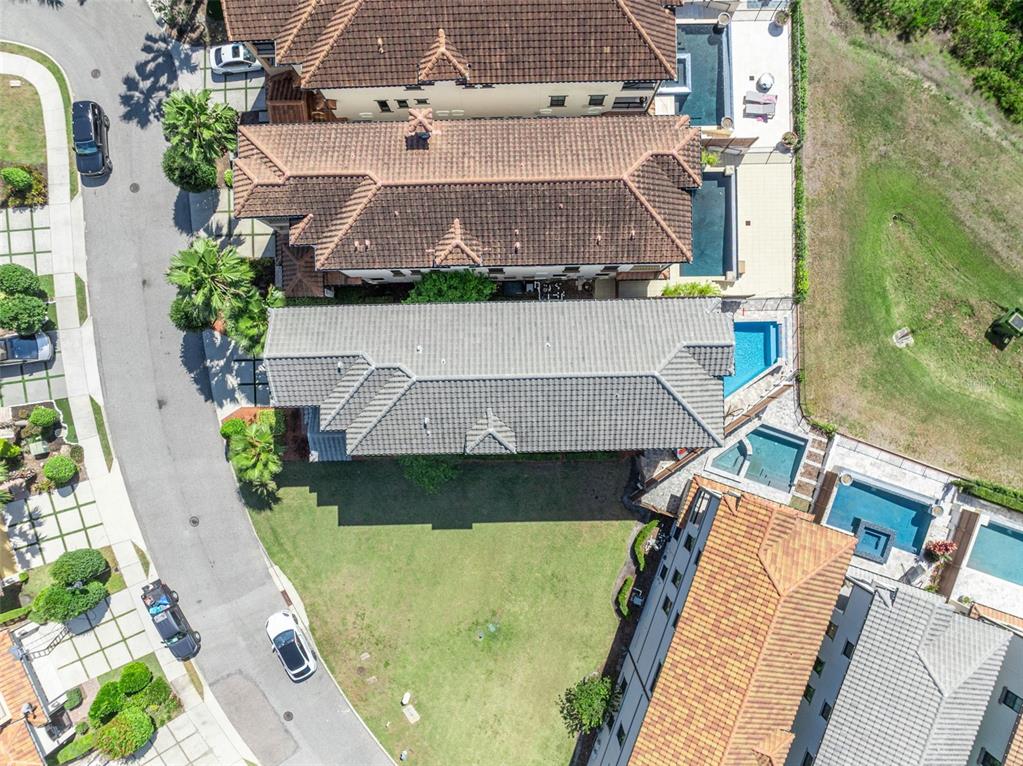 An aerial view shows several houses with tiled roofs, swimming pools, and a curved street — 7613 TOSCANA BOULEVARD, ORLANDO, FL
