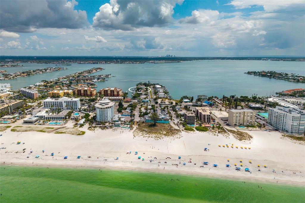 An aerial view of a sandy beach, coastal buildings, and a bay under a cloudy sky — 216 PUNTA VISTA DRIVE, ST PETE BEACH, FL