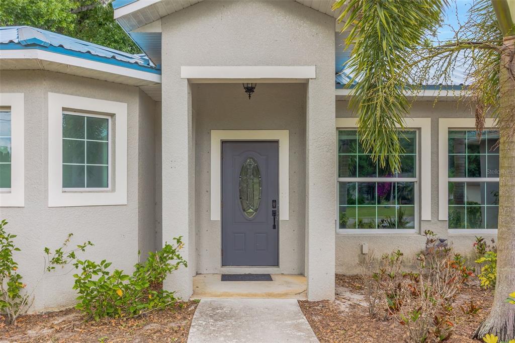 The exterior of a house features a gray front door, stucco walls, and a walkway — 2936 SE NORMAN AVENUE, ARCADIA, FL