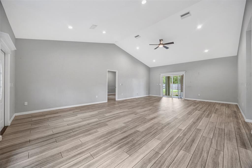 A spacious living room features light gray walls, vaulted ceilings, and wood-look tile flooring — 2936 SE NORMAN AVENUE, ARCADIA, FL