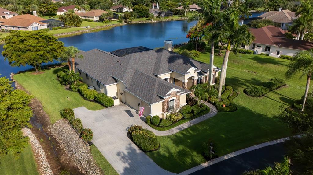 A backyard view of a house with a large screened-in pool enclosure and patio — 15220 BLACKHAWK DRIVE, FORT MYERS, FL