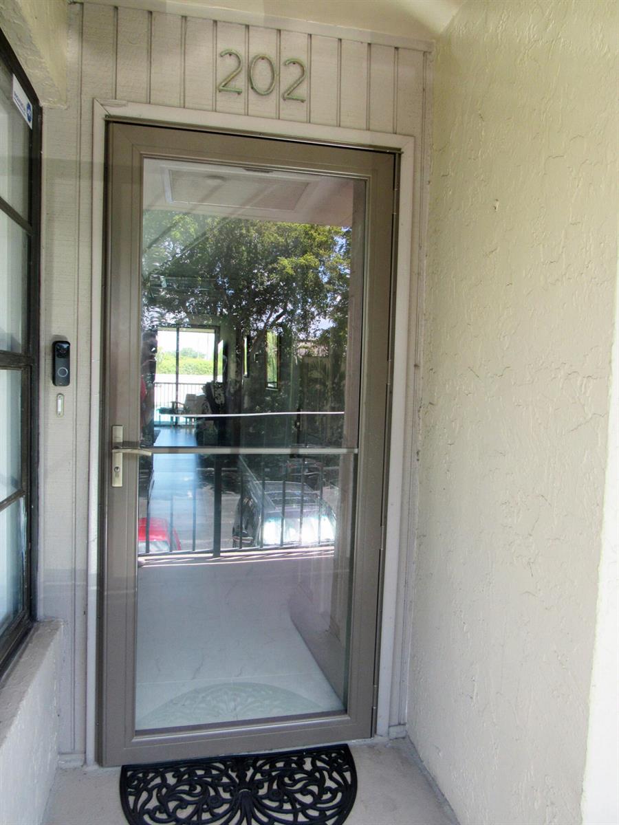 A glass storm door with a silver handle is installed at the entrance of unit 202 — 21 Royal Palm Way # 2020, Boca Raton FL 33432, BOCA RATON, FL