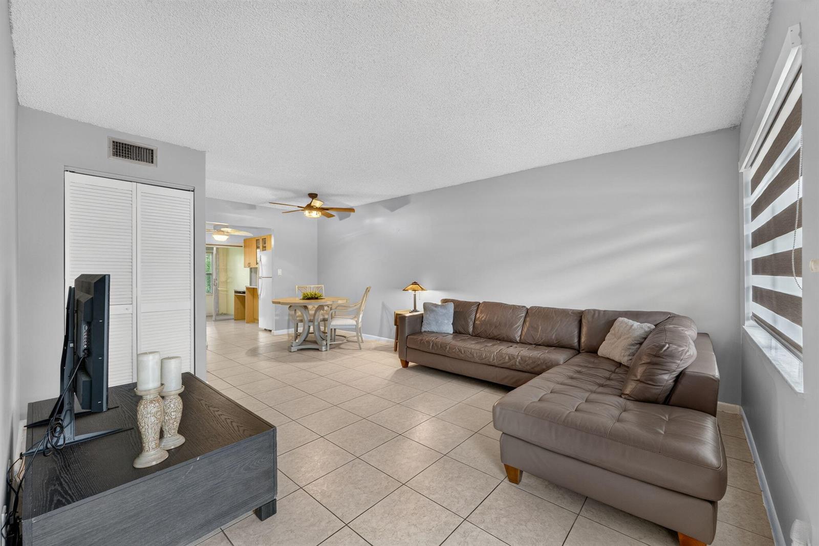 A living room features light tile flooring, a brown sectional sofa, and an adjacent dining area — 251 NW 76th Avenue # 105, Margate FL 33063, MARGATE, FL