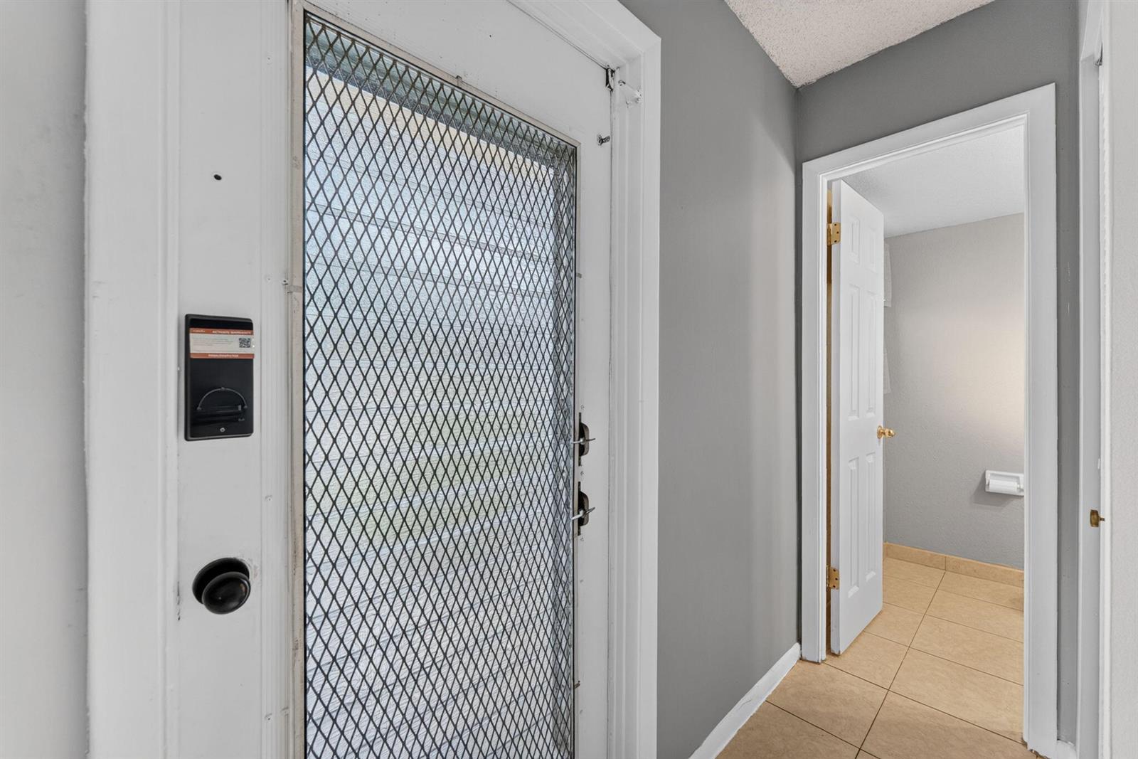 A white security screen door opens into a hallway with gray walls and tile flooring — 251 NW 76th Avenue # 105, Margate FL 33063, MARGATE, FL