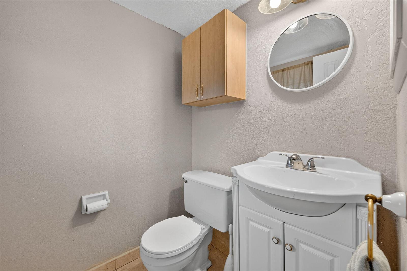 A small bathroom features a white pedestal vanity, a toilet, and a light wood cabinet — 251 NW 76th Avenue # 105, Margate FL 33063, MARGATE, FL