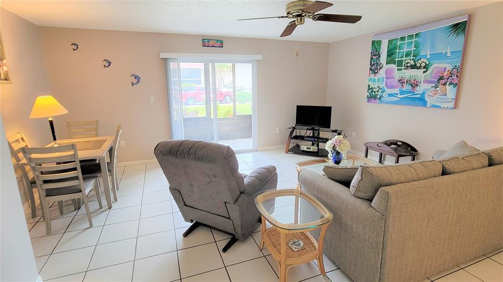 A living and dining area with tile floors, a ceiling fan, and a sliding glass door — 2727 75TH ST W UNIT 7A2, BRADENTON, FL