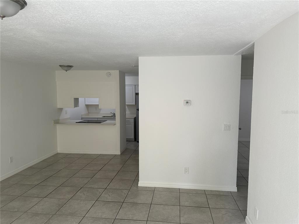 A view of a kitchen with white cabinets and a pass-through window from a tiled room — 5200 SE 31ST STREET SE UNIT D, OCALA, FL