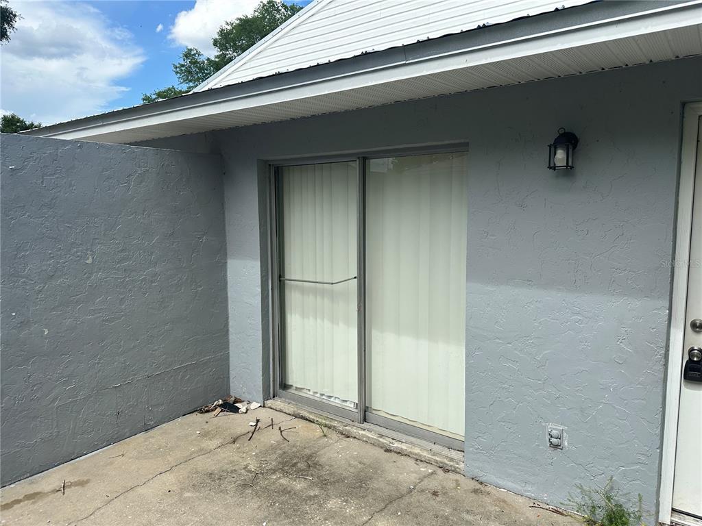 A gray exterior wall features a sliding glass door and a concrete patio area — 5200 SE 31ST STREET SE UNIT D, OCALA, FL