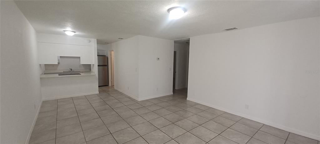 An open-concept living area features white walls, light-colored tile flooring, and a small kitchen — 5200 SE 31ST STREET SE UNIT D, OCALA, FL