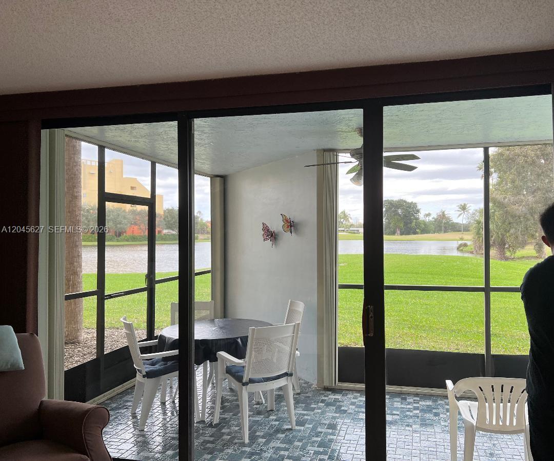 A screened-in patio features tiled flooring, a dining set, and views of a lake — 16325 Golf Club Rd # 111, Weston FL 33326, WESTON, FL