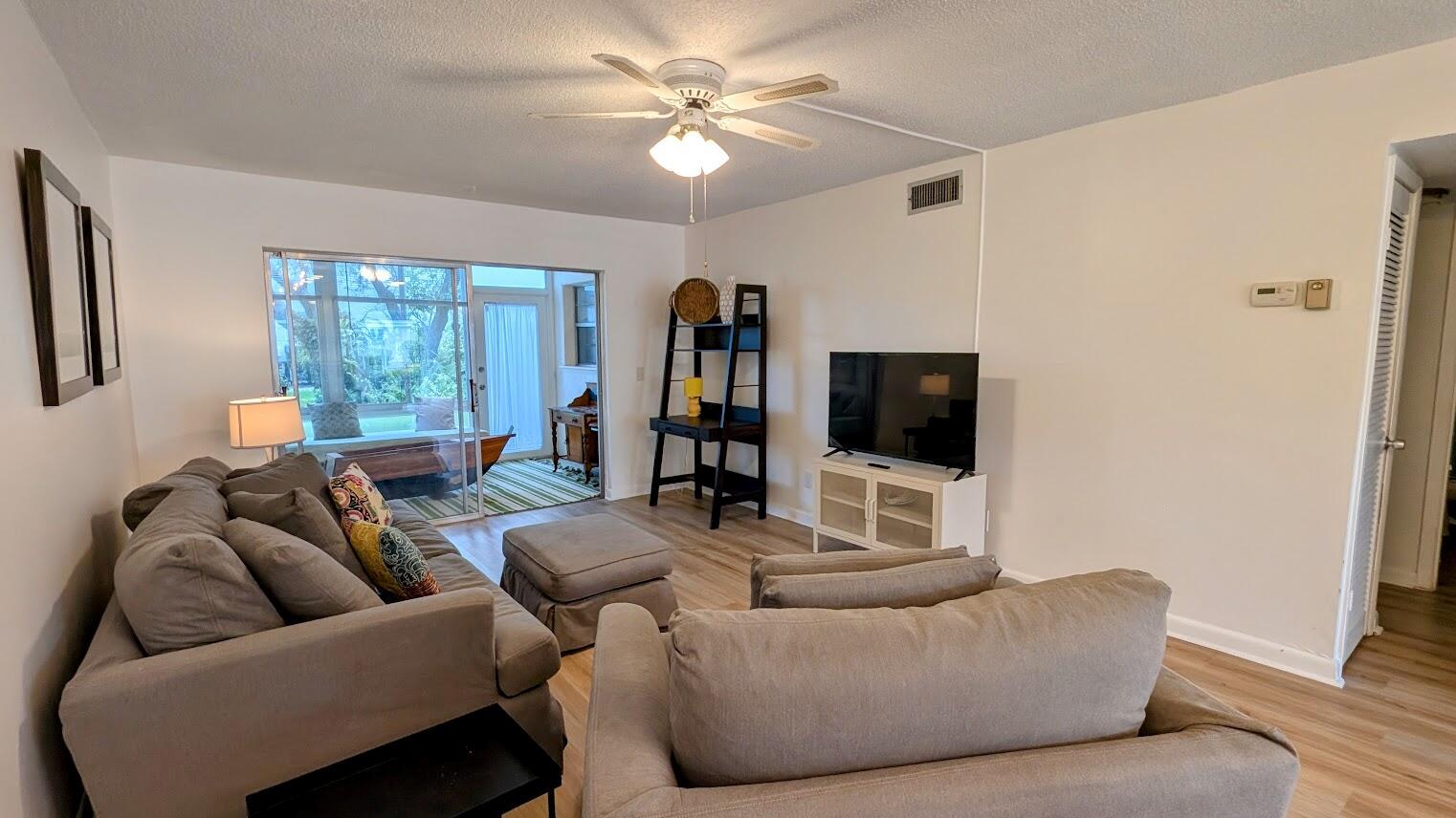 A living room with light wood floors, a ceiling fan, and a sliding glass door — 2950 SE Ocean Boulevard # 2, Stuart FL 34996, STUART, FL