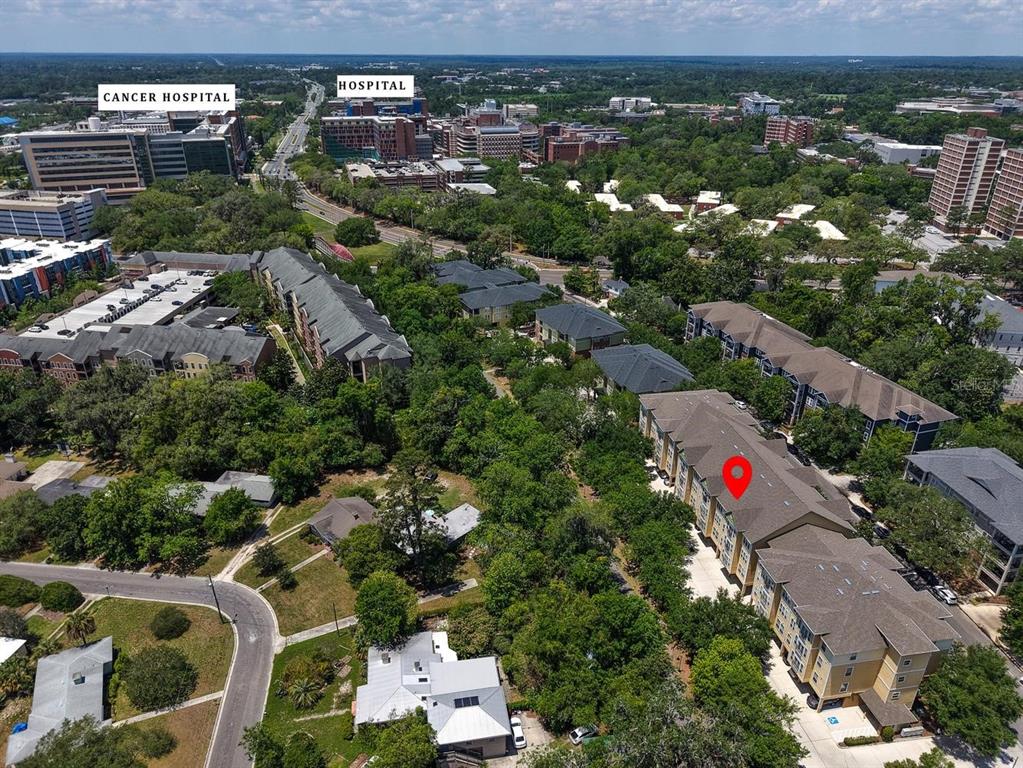 An aerial view shows a multi-story apartment complex surrounded by trees near a hospital district — 1185 SW 9TH ROAD UNIT 212, GAINESVILLE, FL