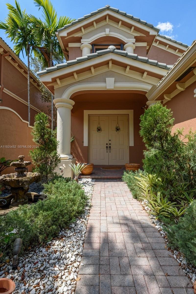 A brick walkway leads to the double front doors of a stucco house with landscaping — 2782 Kinsington Cir # 4, Weston FL 33332, WESTON, FL