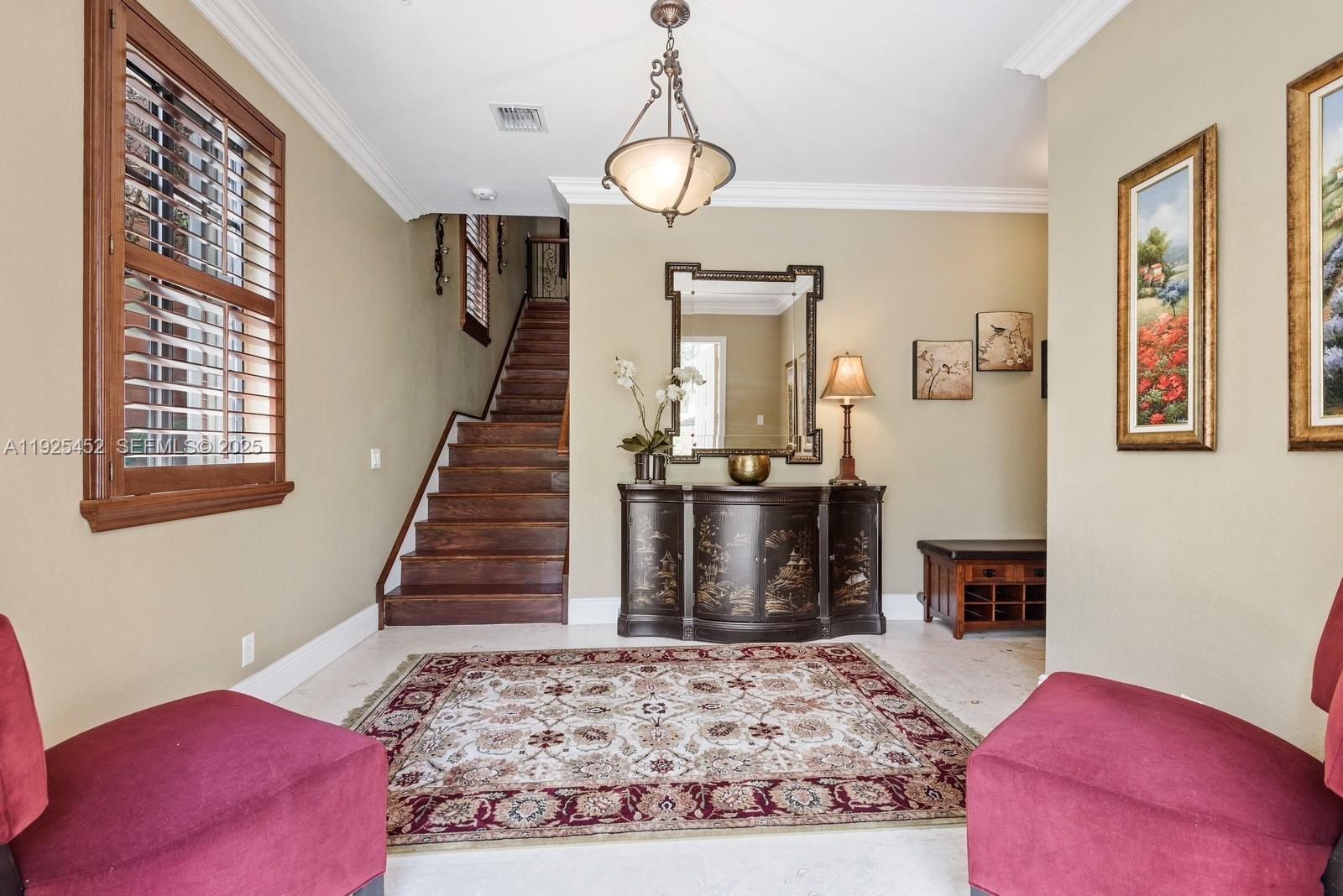 An entryway features a staircase, a decorative cabinet with a mirror, and two red chairs — 2782 Kinsington Cir # 4, Weston FL 33332, WESTON, FL