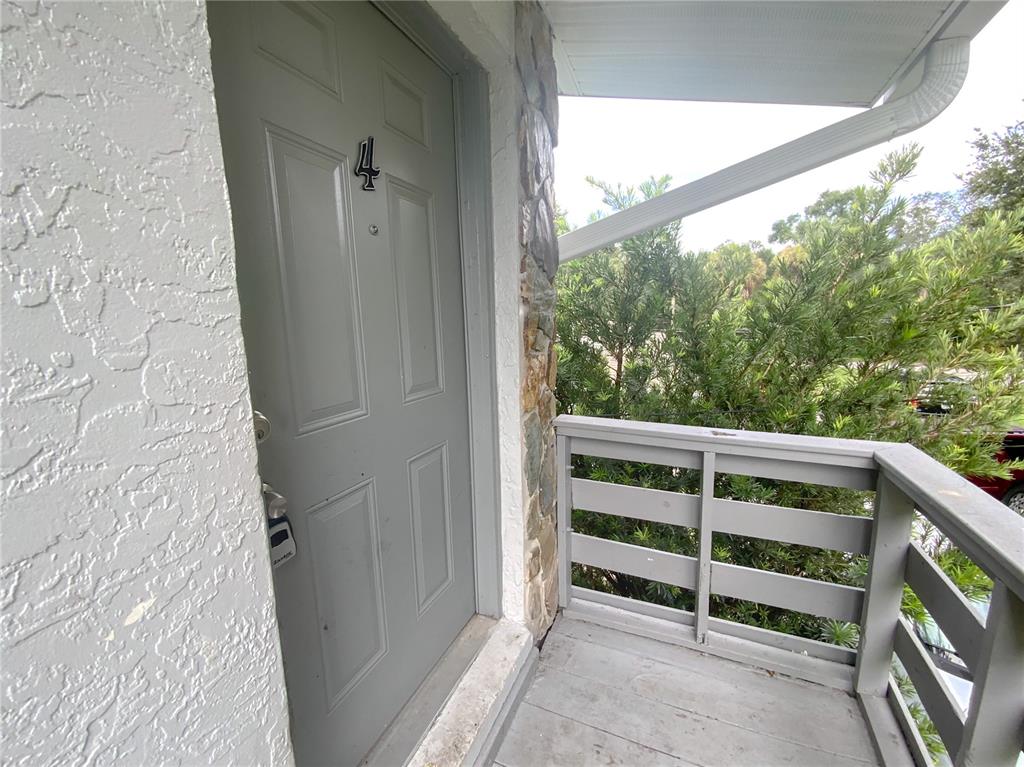 A grey door with the number four sits on a small balcony with wooden railings — 2205 IRENE STREET UNIT 4, LUTZ, FL
