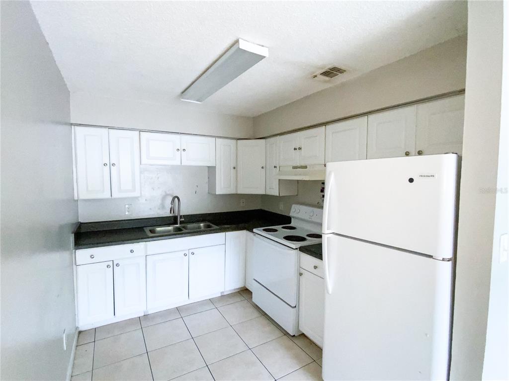 A kitchen features white cabinets, a dark countertop, a white stove, and a white refrigerator — 2205 IRENE STREET UNIT 4, LUTZ, FL