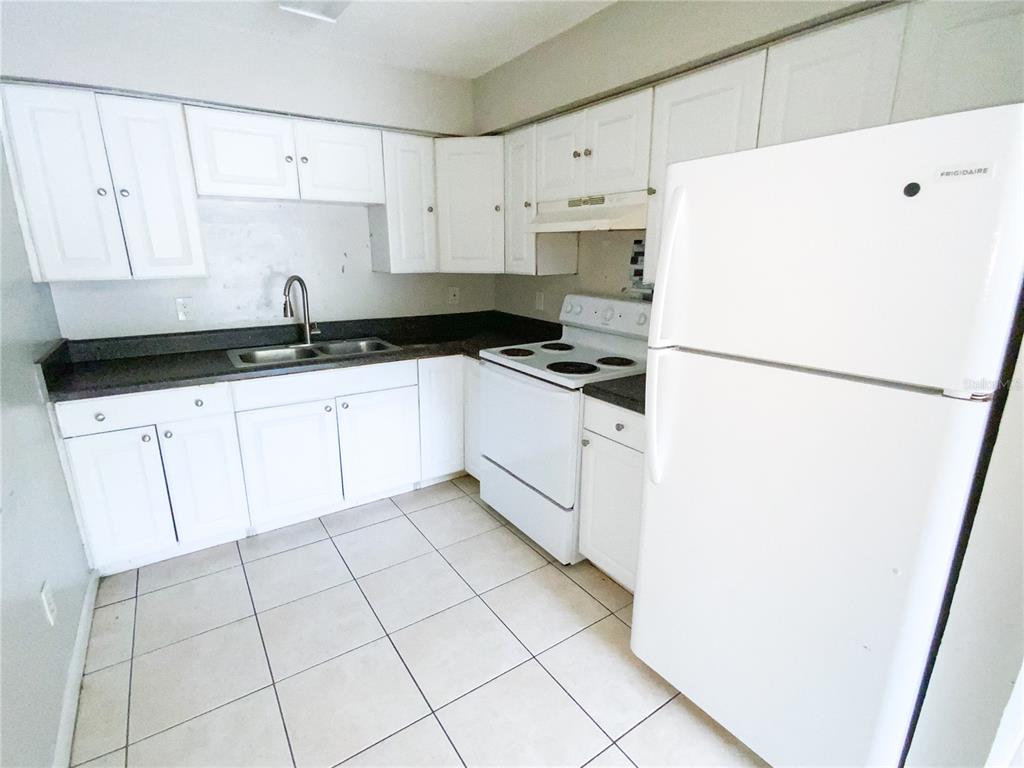 A kitchen features white cabinets, white appliances, dark countertops, and light-colored floor tiles — 2205 IRENE STREET UNIT 4, LUTZ, FL