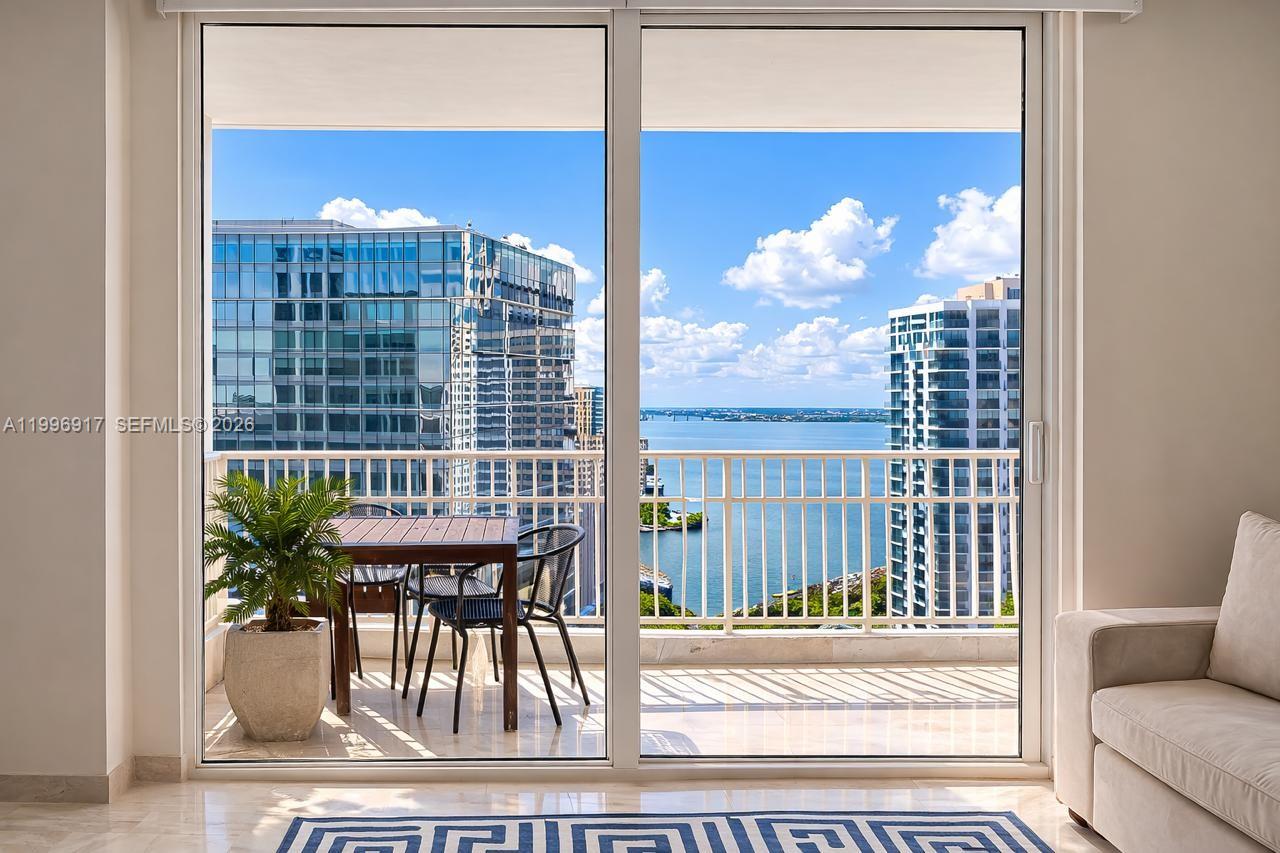 A balcony with a table and chairs overlooks a bay and city skyline — 701 Brickell Key Blvd # 1611, Miami FL 33131, MIAMI, FL