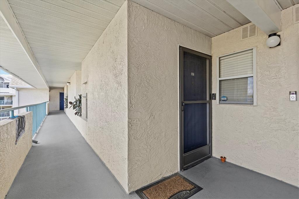 An exterior view of an apartment building walkway with a screen door and stucco walls — 5537 SEA FOREST DRIVE UNIT 307, NEW PORT RICHEY, FL