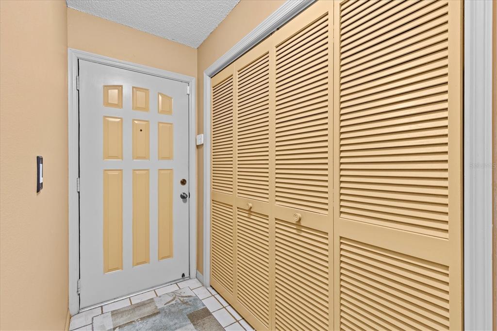 An entryway features a white door, a tiled floor, and a large louvered closet — 5537 SEA FOREST DRIVE UNIT 307, NEW PORT RICHEY, FL