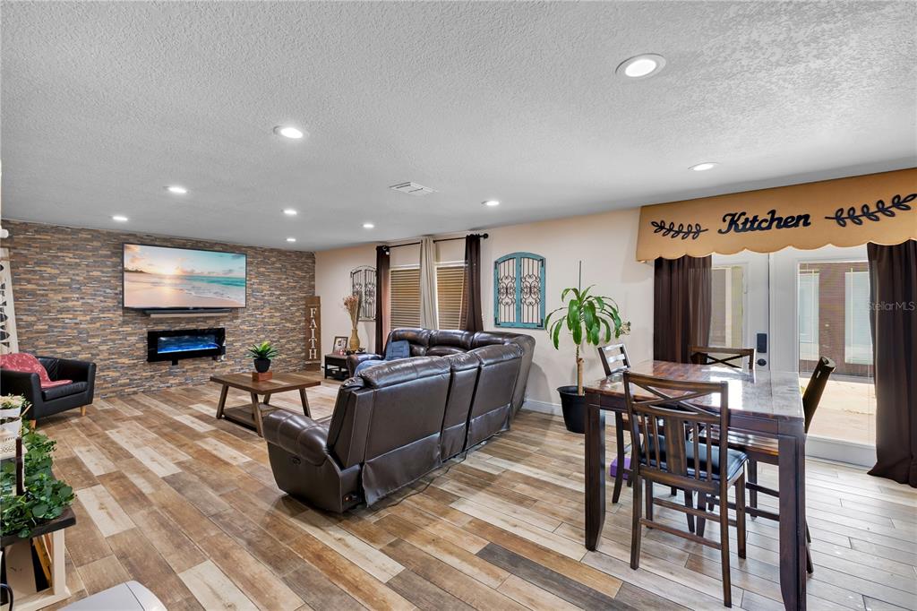 An open-concept living and dining area features wood-look tile flooring and a stone accent wall — 5051 PLYMOUTH TURTLE CIRCLE, ST CLOUD, FL