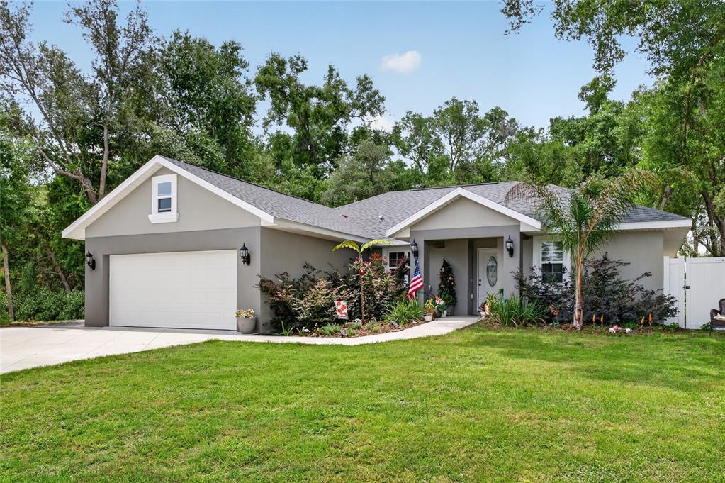 A single-story gray house with a two-car garage, a front porch, and a grassy lawn — 8160 SE 164TH PLACE, SUMMERFIELD, FL