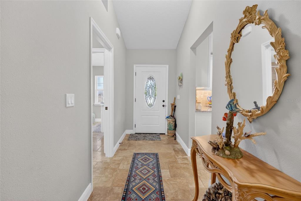 A tiled entryway features a white front door, a decorative mirror, and a console table — 8160 SE 164TH PLACE, SUMMERFIELD, FL