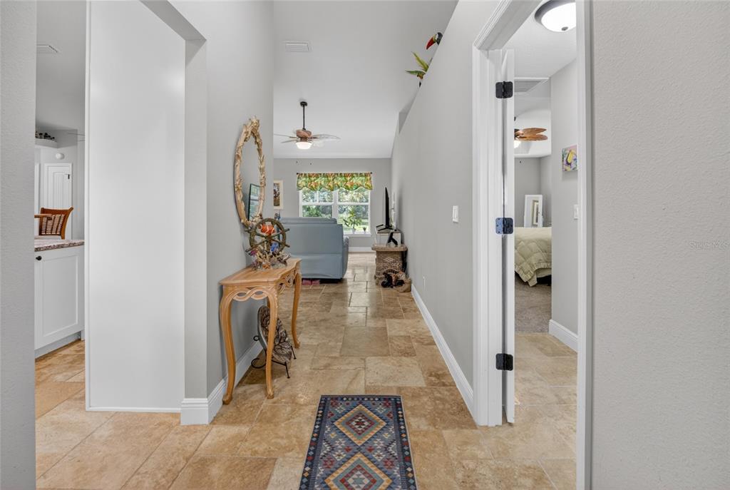 A hallway with tile flooring leads to a living area, with a bedroom doorway on the right — 8160 SE 164TH PLACE, SUMMERFIELD, FL