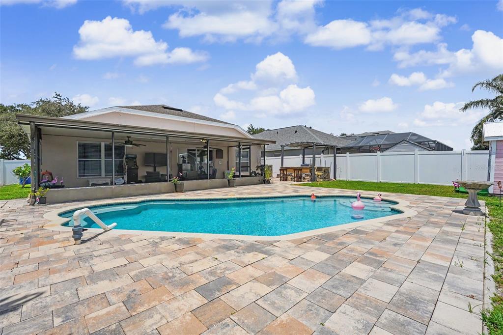 A backyard features a swimming pool, a screened-in patio, and a paved stone deck — 11531 MISTY ISLE LANE, RIVERVIEW, FL