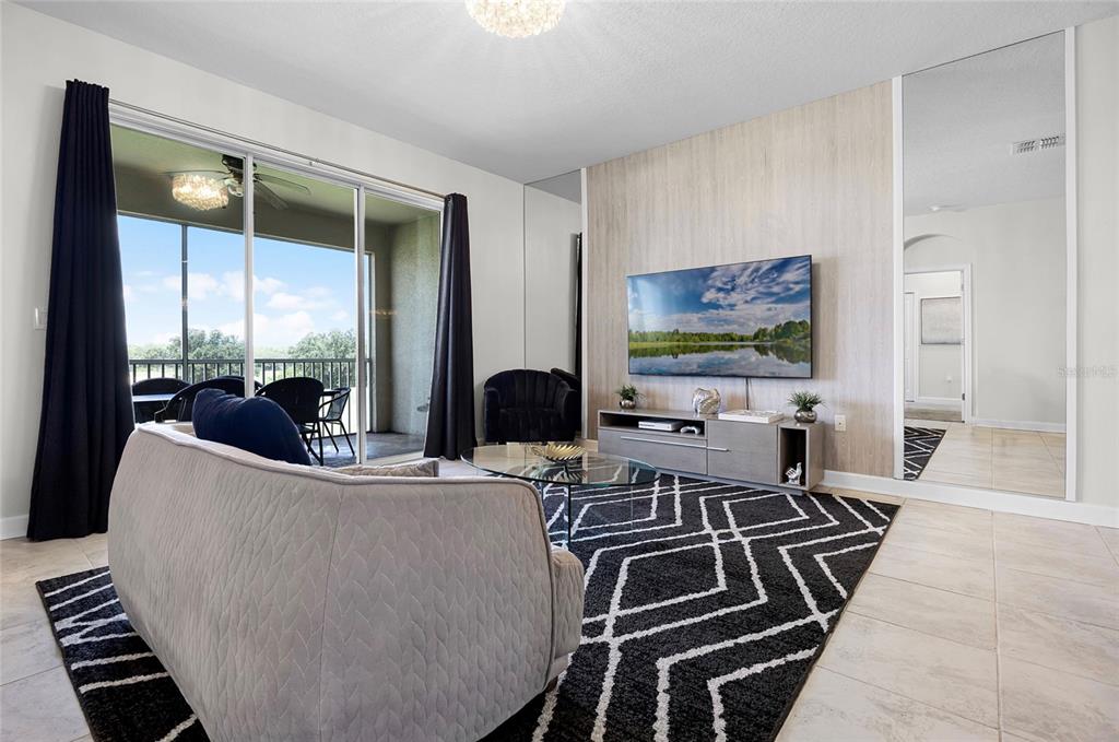 A living room features a patterned rug, a wall-mounted television, and sliding glass balcony doors — 543 OCEAN COURSE AVENUE, DAVENPORT, FL