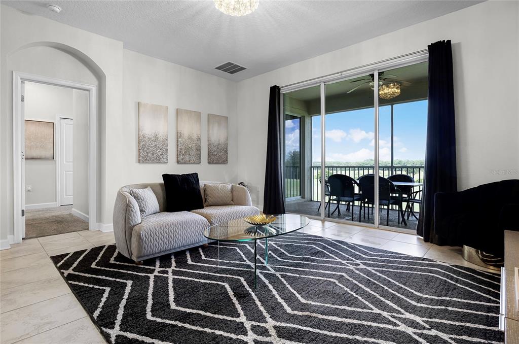 A living room features a patterned rug, a sofa, a glass coffee table, and sliding doors — 543 OCEAN COURSE AVENUE, DAVENPORT, FL