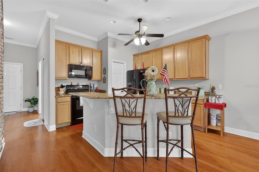 A kitchen features light wood cabinets, granite countertops, a breakfast bar, and hardwood flooring — 1010 GREEN GATE BOULEVARD, GROVELAND, FL