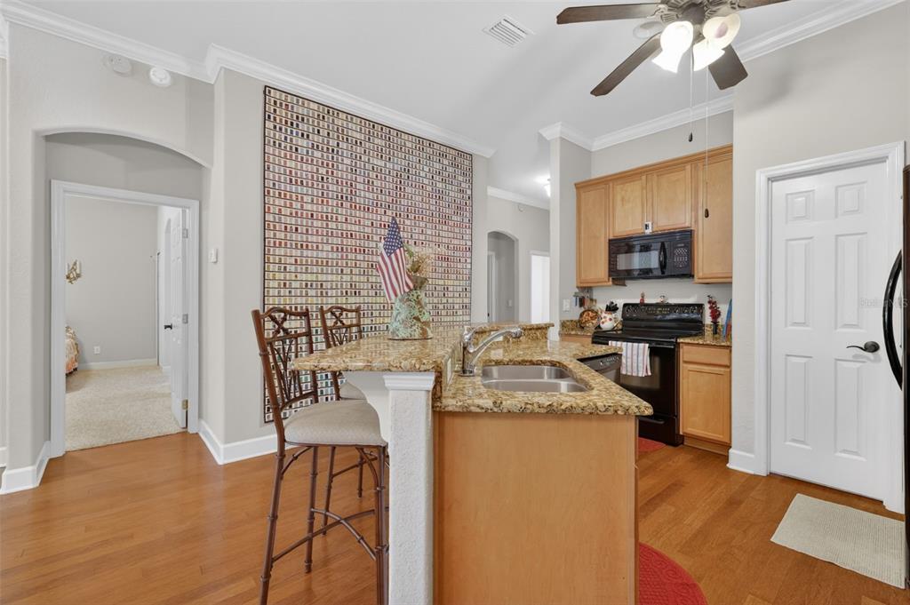 A kitchen with a granite-topped island, wooden cabinets, and a large wall art display — 1010 GREEN GATE BOULEVARD, GROVELAND, FL