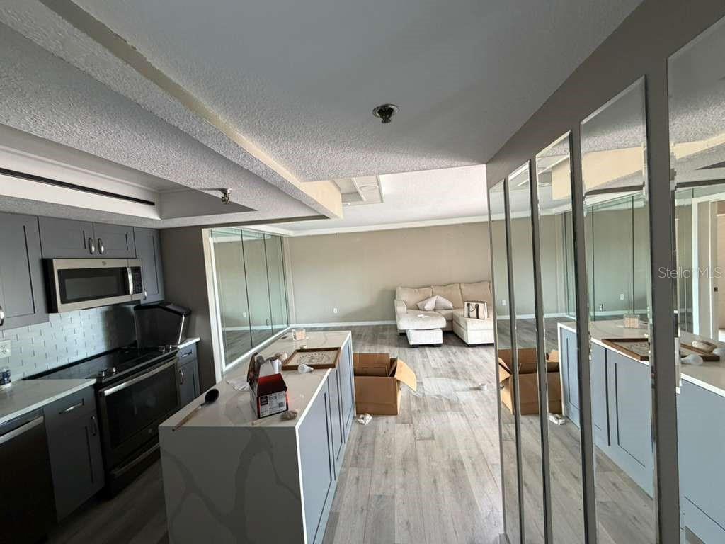 A kitchen with a central island and gray cabinetry opens into a living area — 7432 SUNSHINE SKYWAY LANE S UNIT 206, ST PETERSBURG, FL