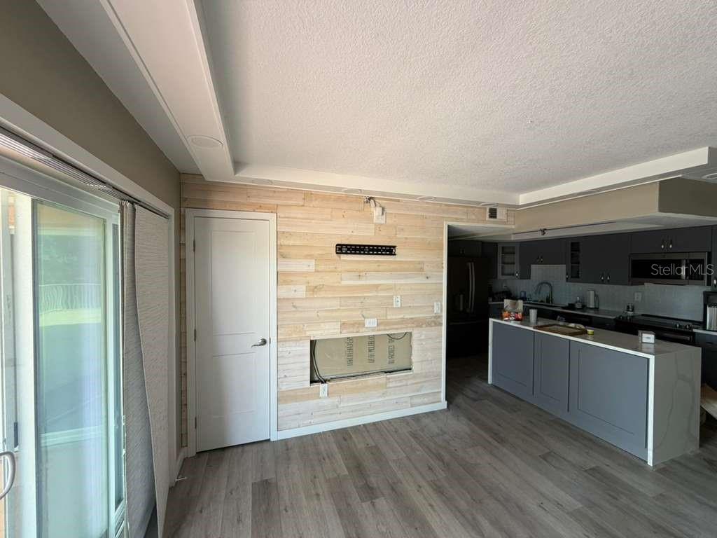 A living room with wood-plank accent walls, a fireplace opening, and an adjacent kitchen — 7432 SUNSHINE SKYWAY LANE S UNIT 206, ST PETERSBURG, FL