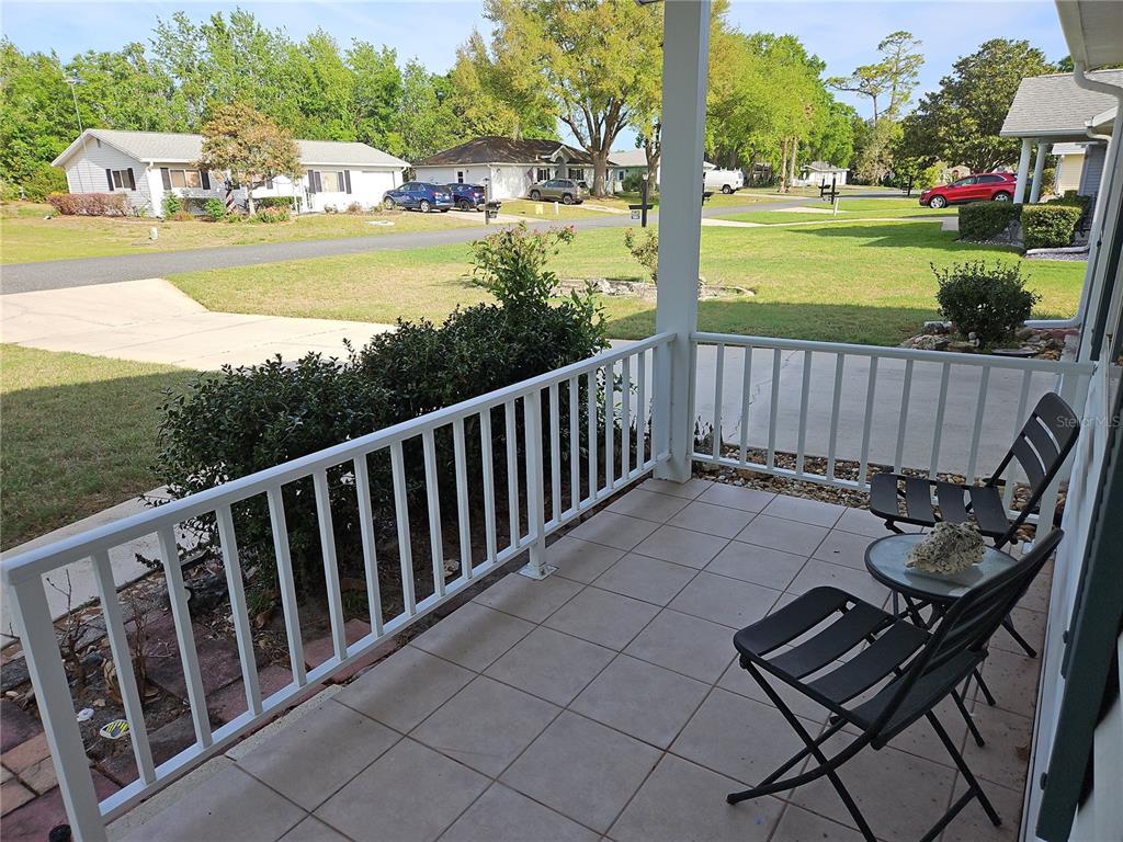 A tiled porch with white railings, two chairs, and a small table overlooking a neighborhood — 11087 SW 77TH COURT, OCALA, FL